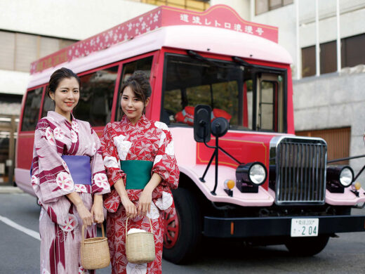 画像：レトロなボンネットバスの前で微笑む色浴衣を着た二人の女性